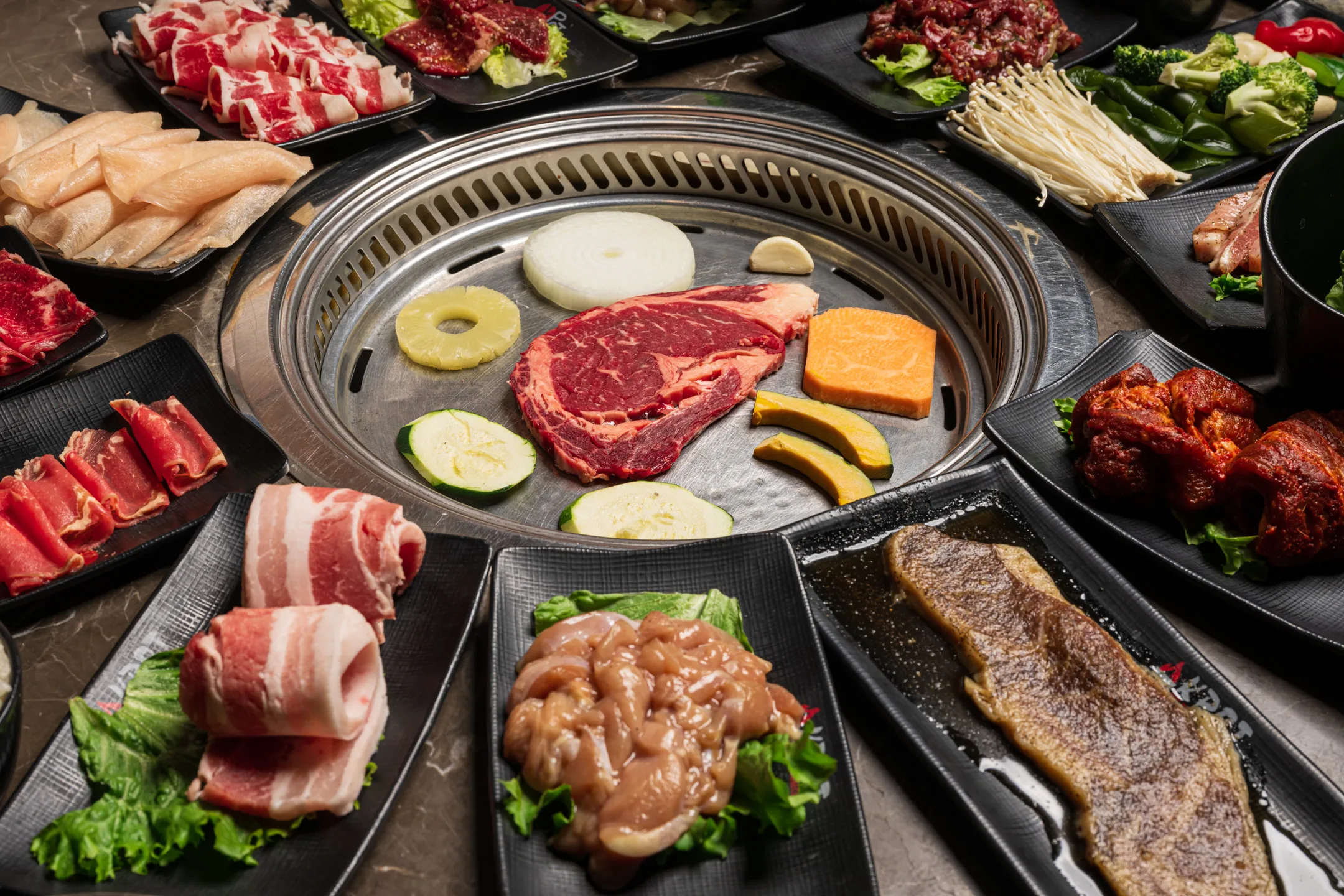 Grilling table at KPOT with meats and vegetables
