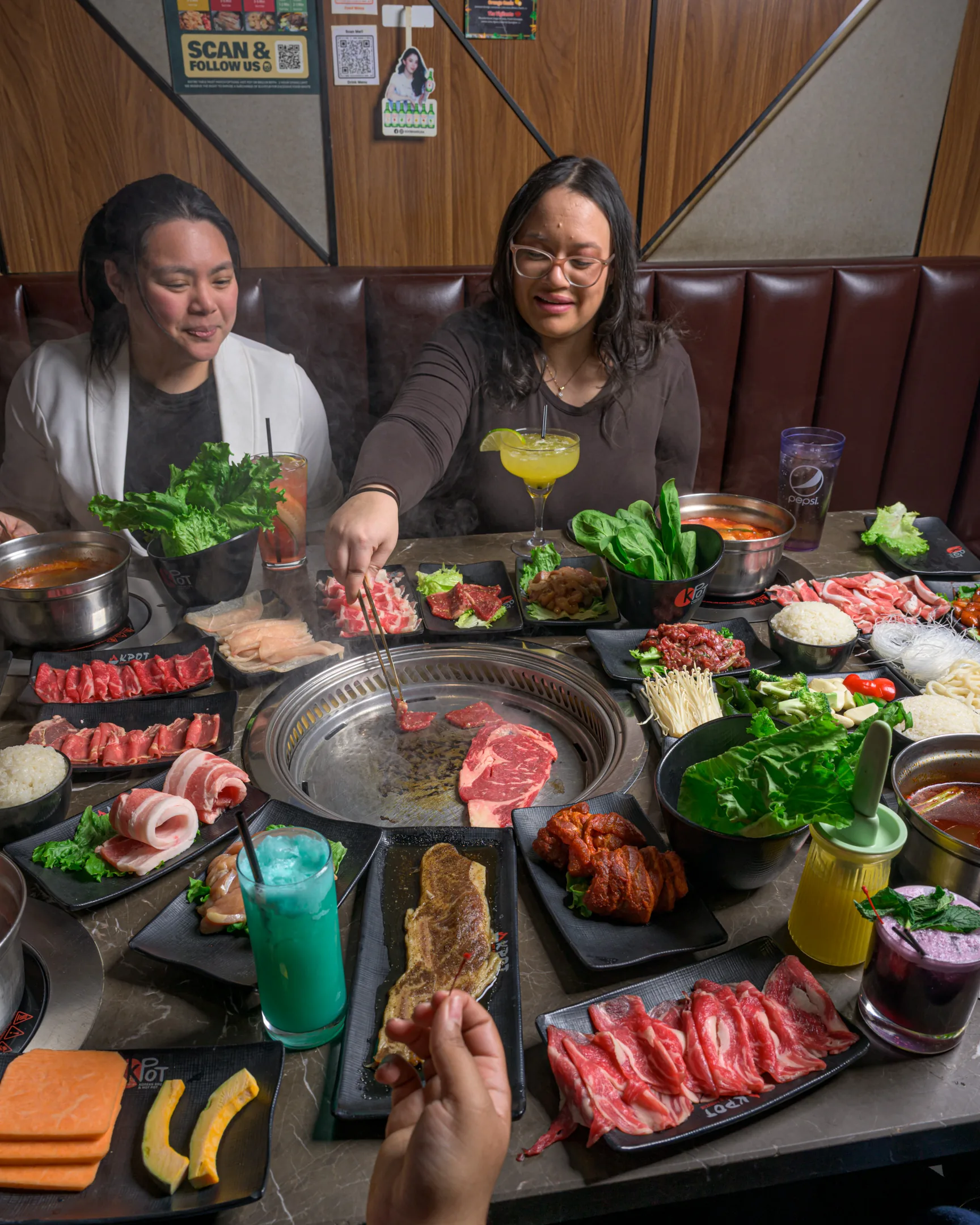 Two people grilling meat at a KPOT table