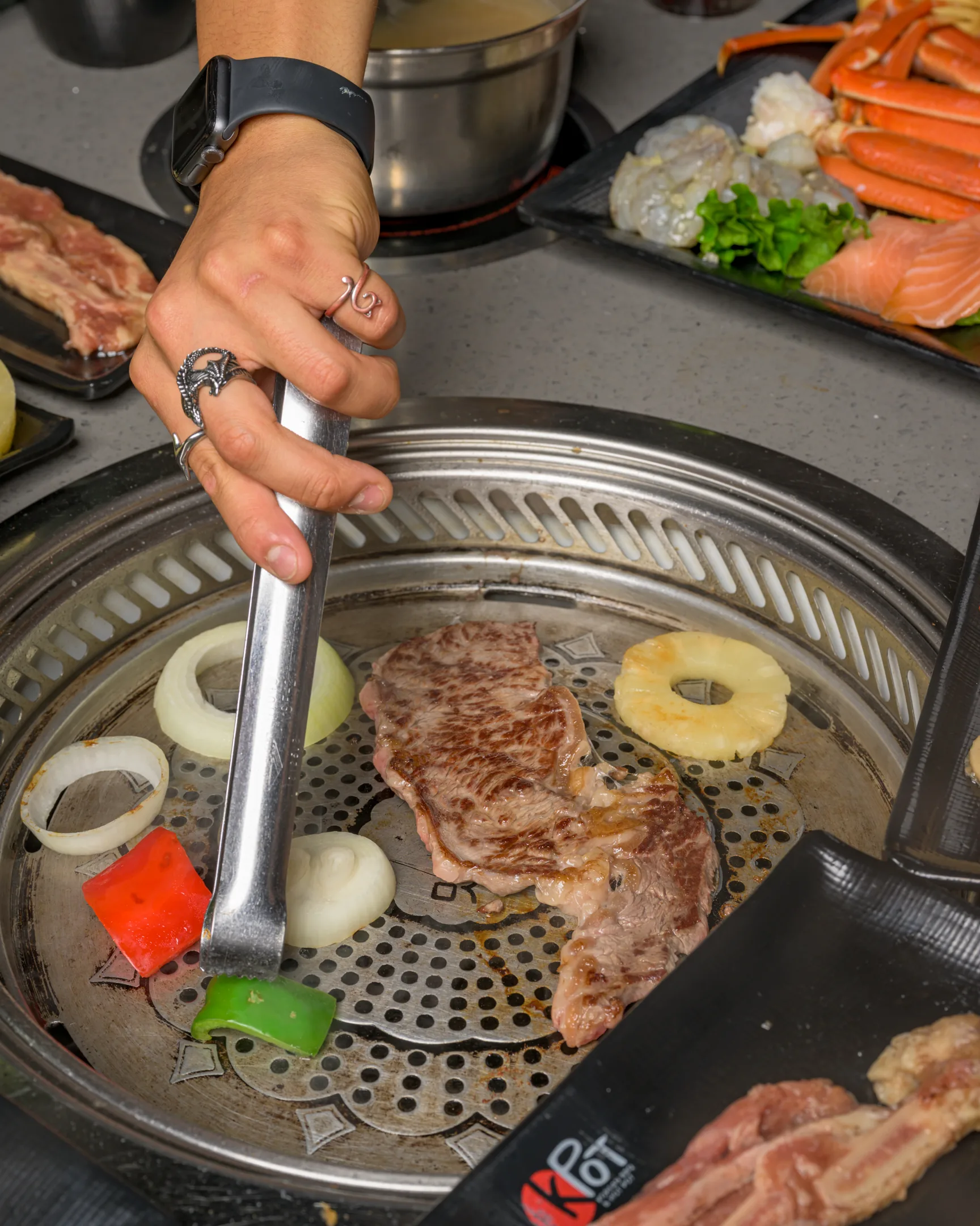 Person grilling vegetables and meat at KPOT